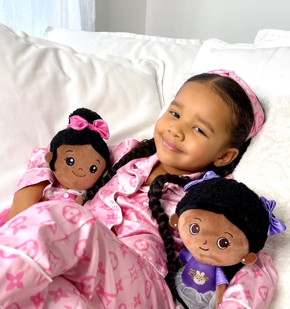 Lynnie is smiling and she is lying in the bed together with her new iFrodolls. 